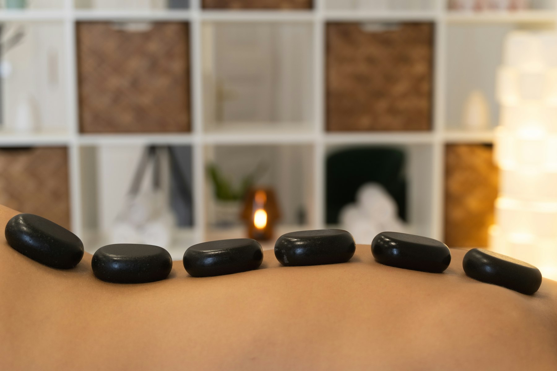 Therapist setting hot stones in a candlelit treatment room